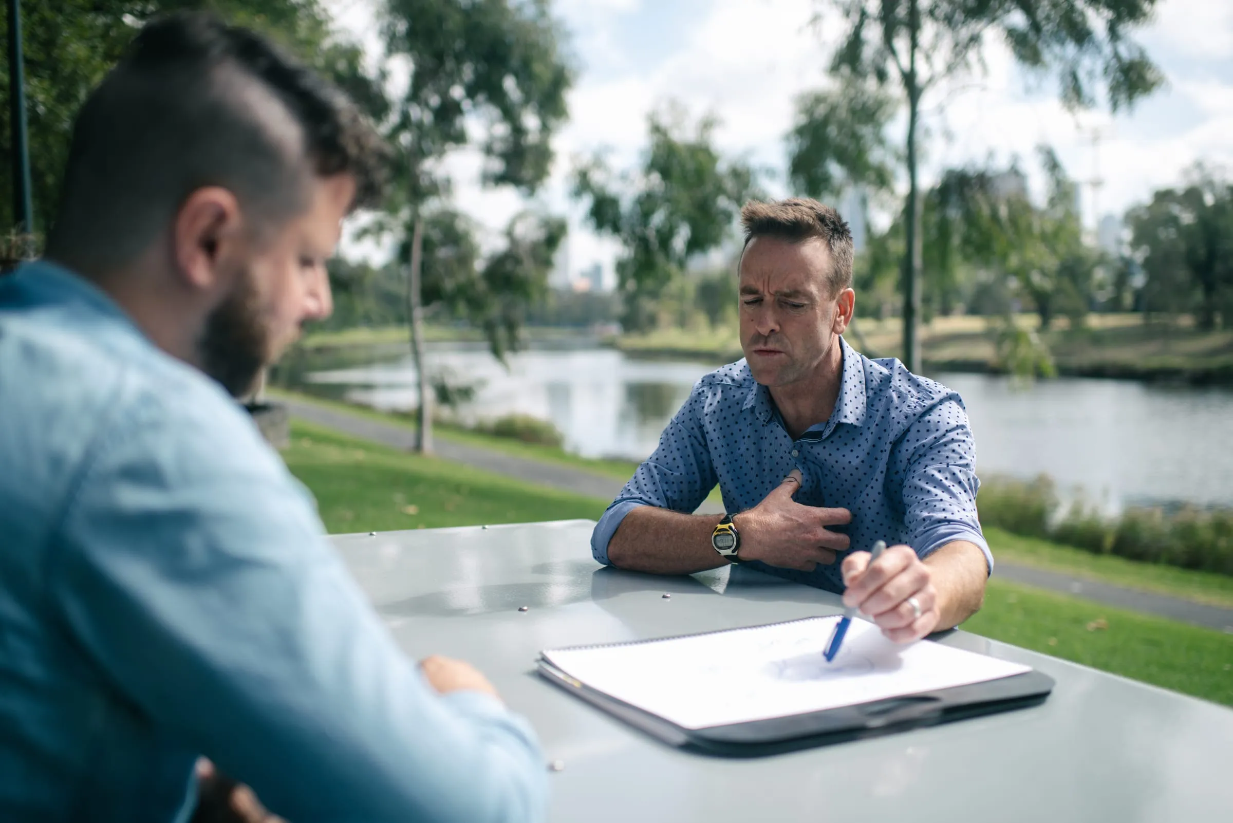 Scott working through notes with a client at a riverside table
